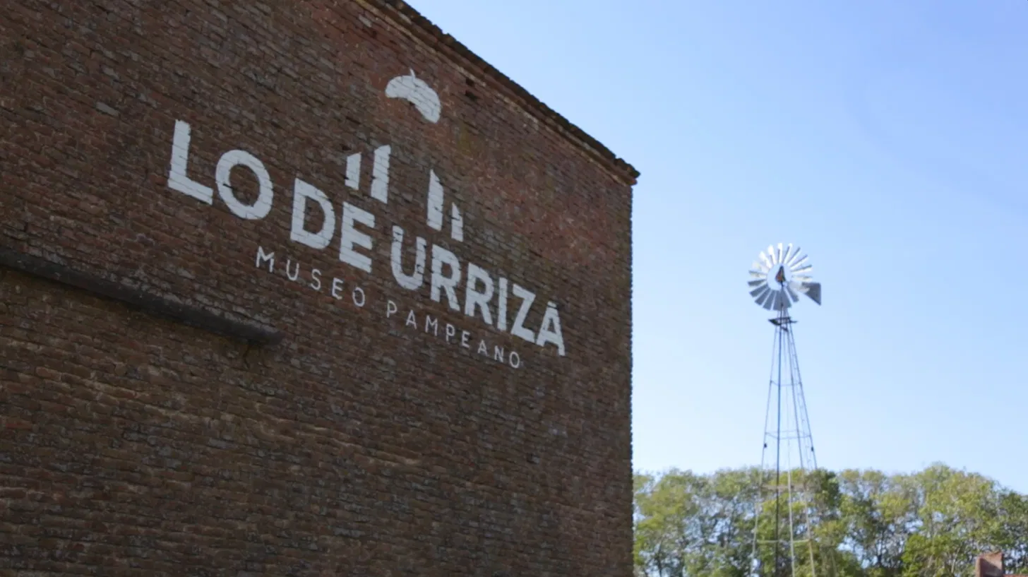 Fachada de ladrillo de Lo de Urriza, Museo Pampeano, con el molino detrás